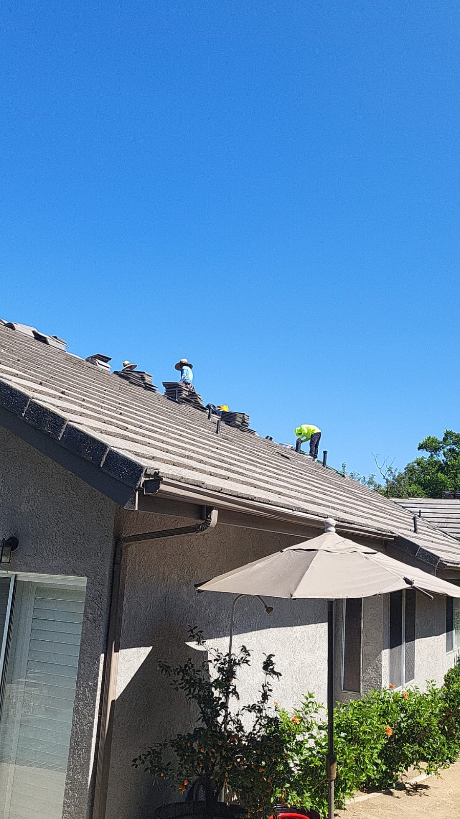 Two roofers installing beige tiles on residential roof